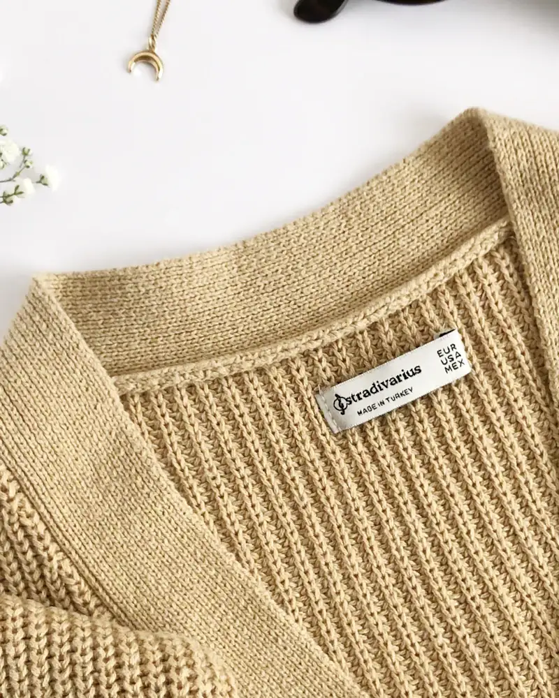 Oat lambswool cardigan laid flat, close-up