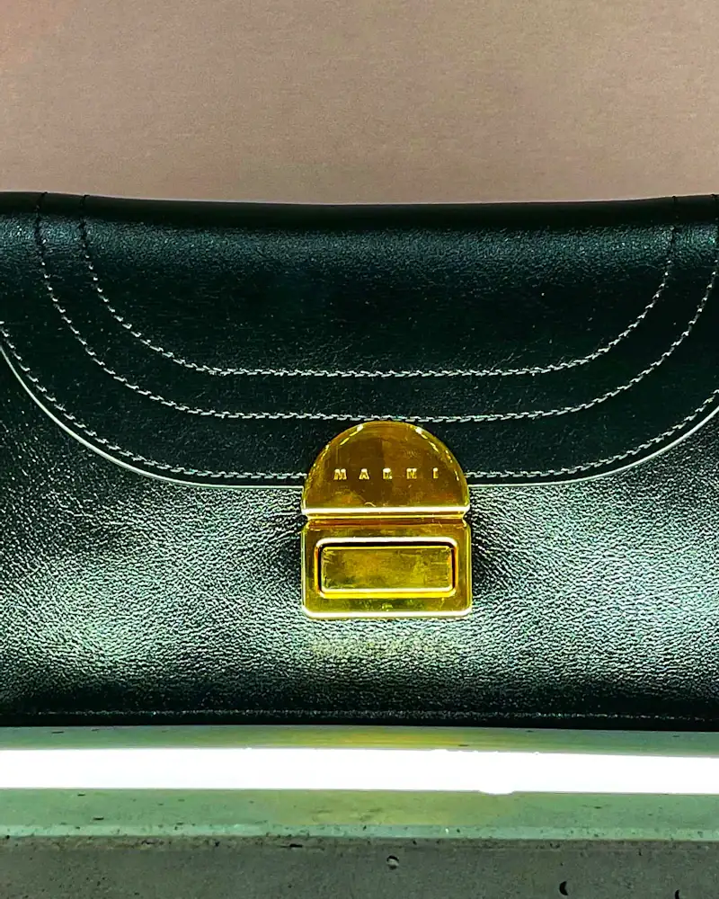Bottle green leather clutch with a gold clasp, close-up