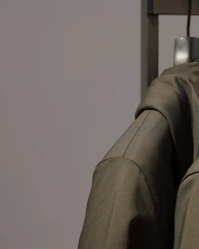 Field green waxed parkas on wall hooks, close-up