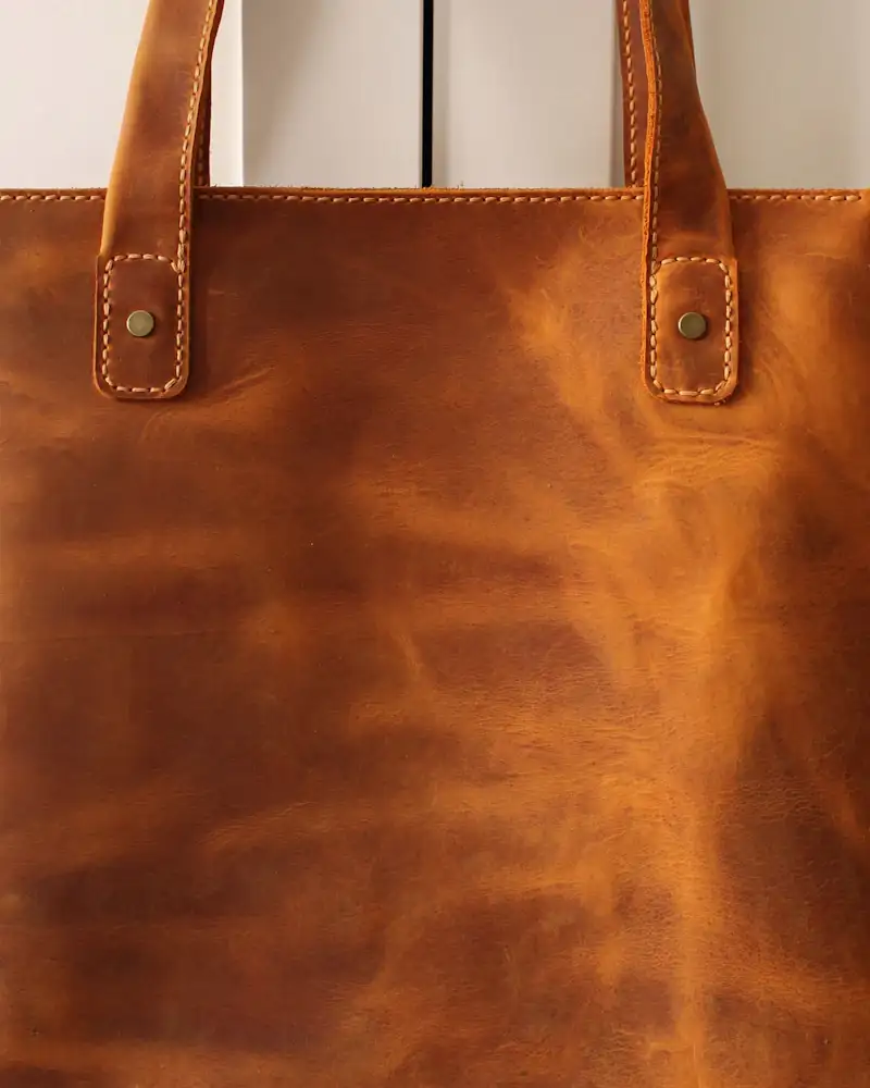 Cognac leather tote hanging on a door, close-up