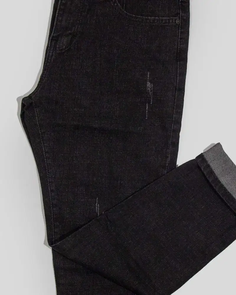 Black trousers folded on a white floor, close-up