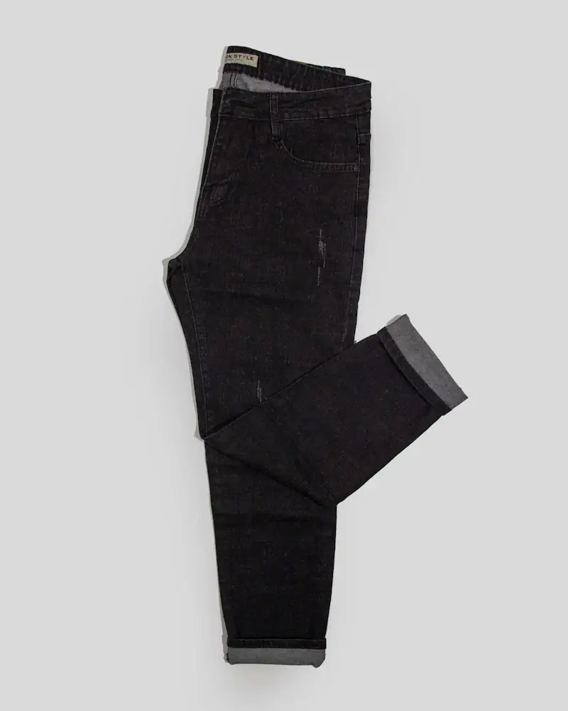 Black trousers folded on a white floor