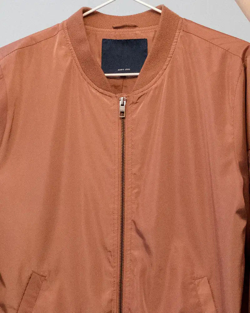 Terracotta zip overshirt on a white hanger, close-up