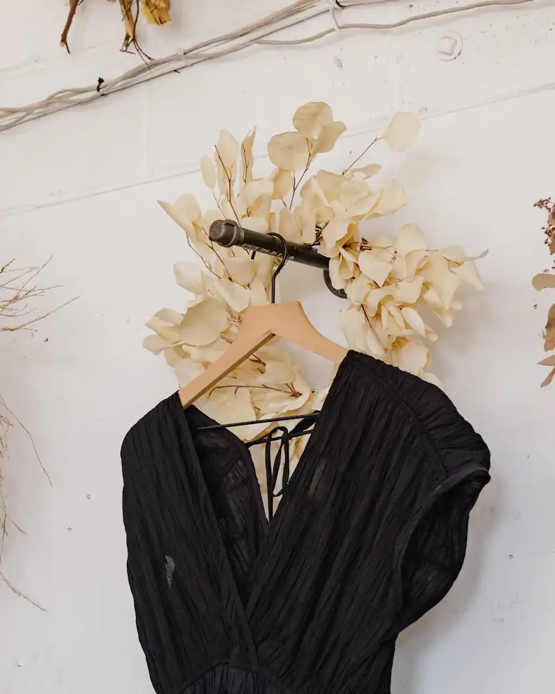 Black crepe midi dress hanging on a white wall, close-up