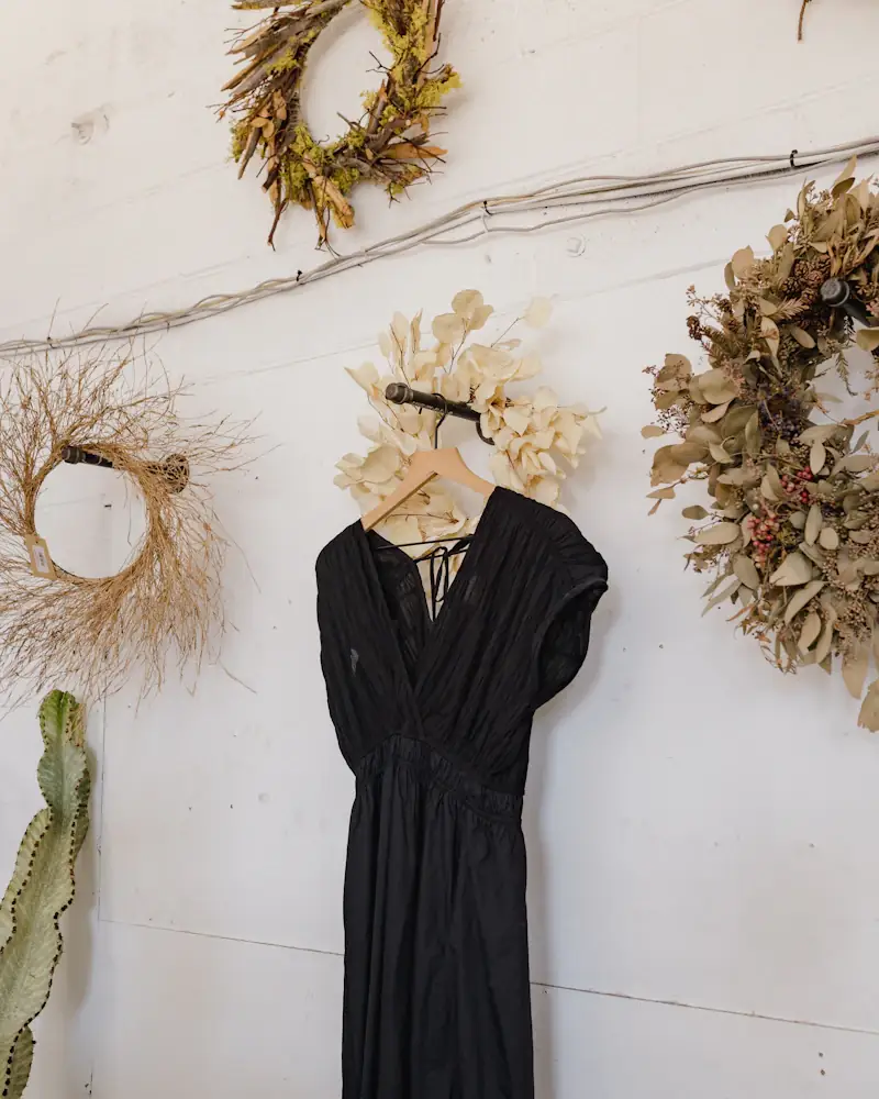Black crepe midi dress hanging on a white wall